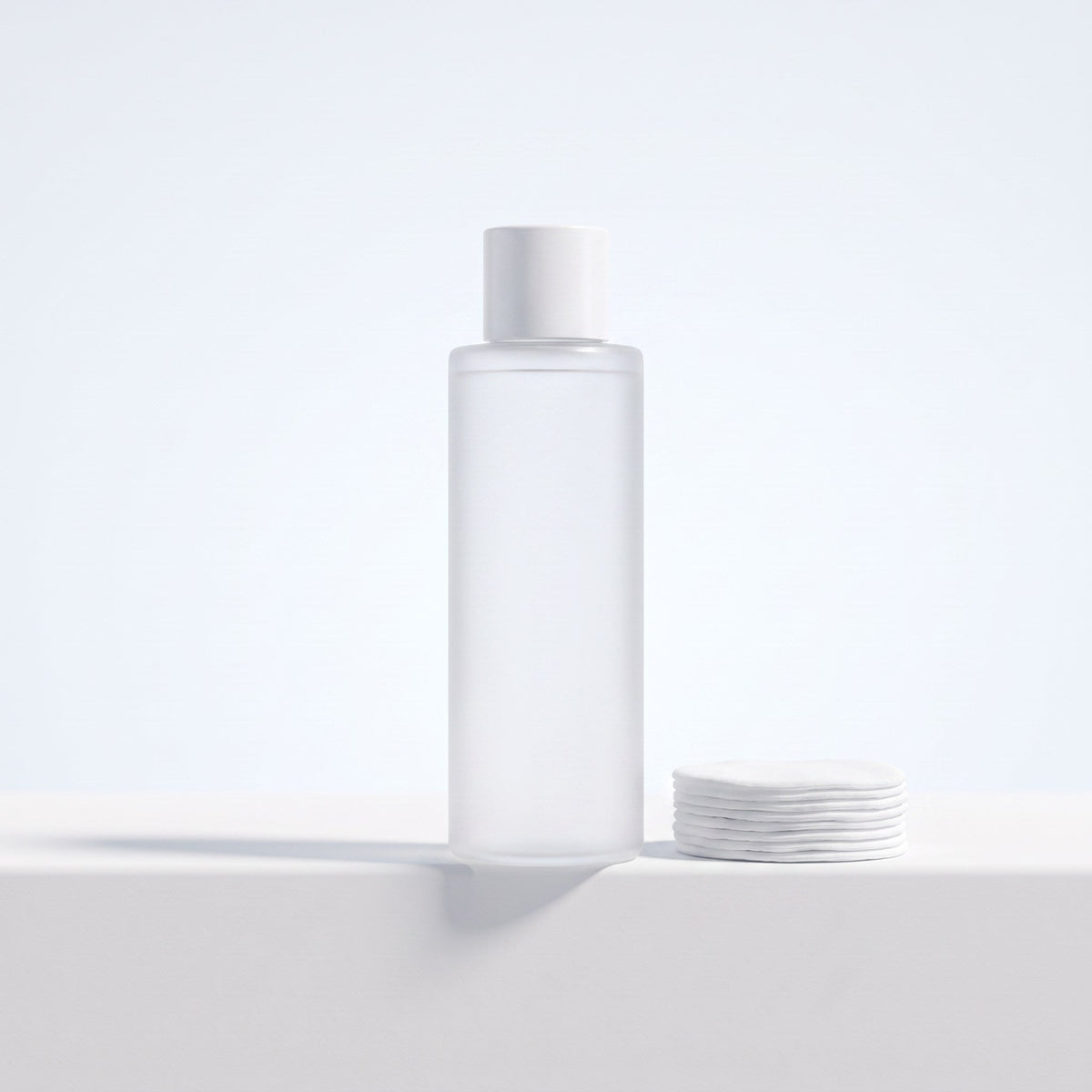 Frosted toner bottle with a stack of cotton pads
